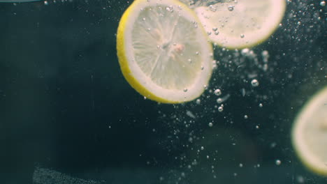 Several-lemon-fruits-fall-inside-a-water-tank-and-disturb-water.-Three-bright-yellow-lemon-fruits-fall-inside-a-water-tank-and-return-to-the-surface